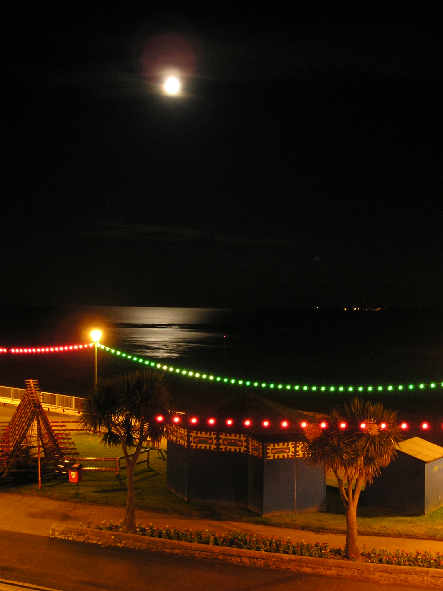Moon and reflection over the swingboats and roundabout from Channel View